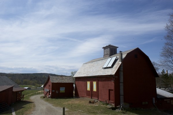 Image of a red barn under a blue sky with sweeping white clouds. 